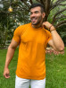 Modelo sorridente de camisa caramelo e bermuda branca, posando em um cenrio natural com rvores ao fundo