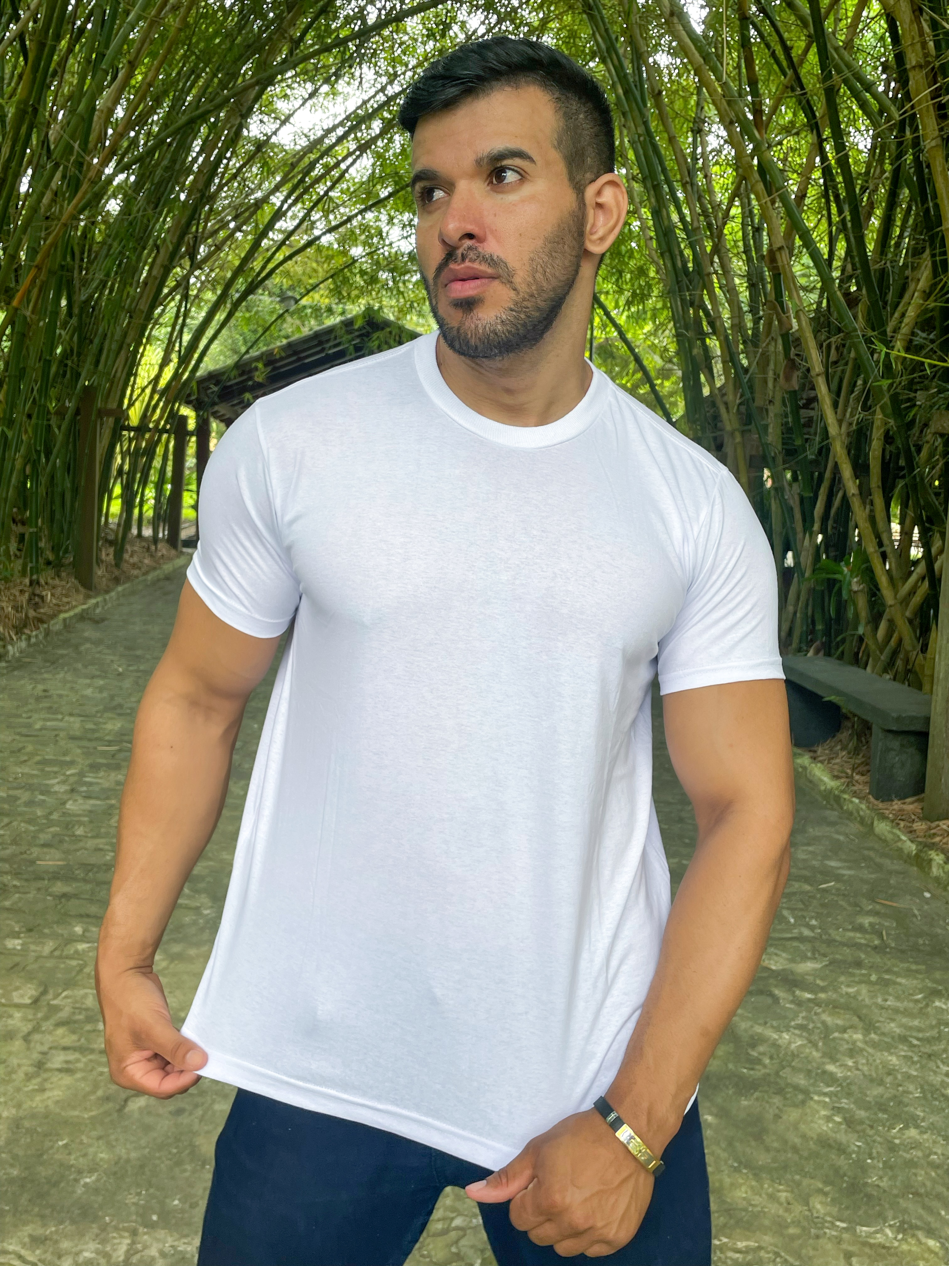 Camiseta Branca Homem posando em ambiente natural com camiseta branca, rodeado por bambus.